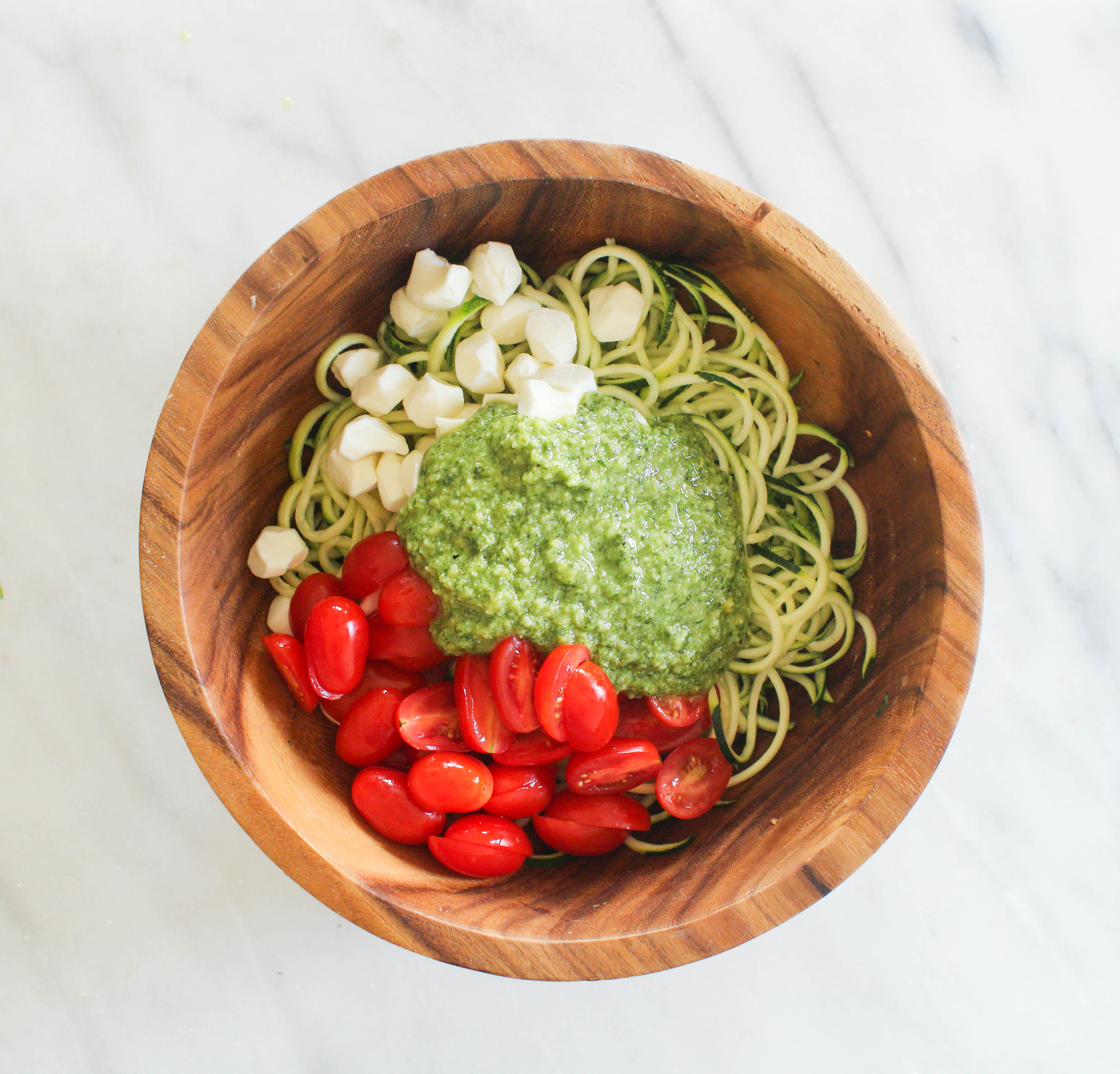  These Pesto Zucchini Noodles are a light and summery dish that doesn’t require a stove top or oven! Simply whip together a fresh basil pesto and toss zucchini noodles with cherry tomatoes and mozzarella pearls.