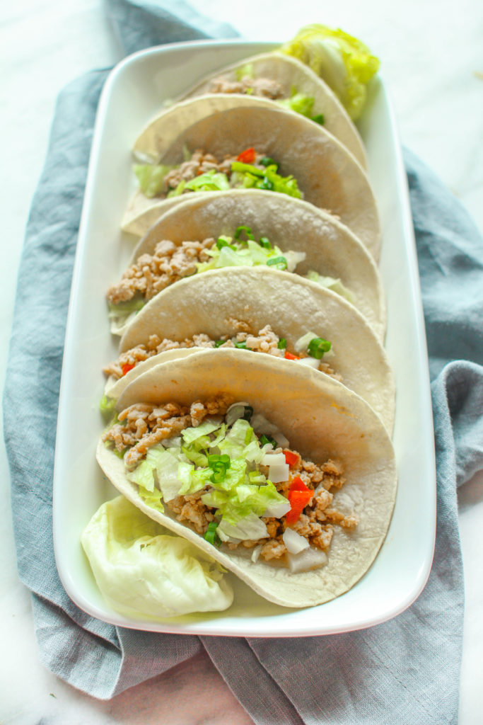 Savory and full of flavor, these Asian chicken tacos are made in the slow cooker and are packed with water chestnuts, brown rice, and topped with crunchy lettuce and green onion.  