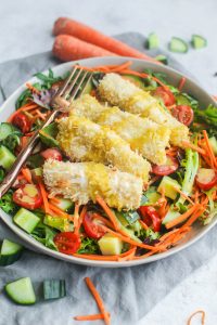 Chicken tenders on a bed of greens with tomatoes, carrots, cucumber and honey mustard dressing