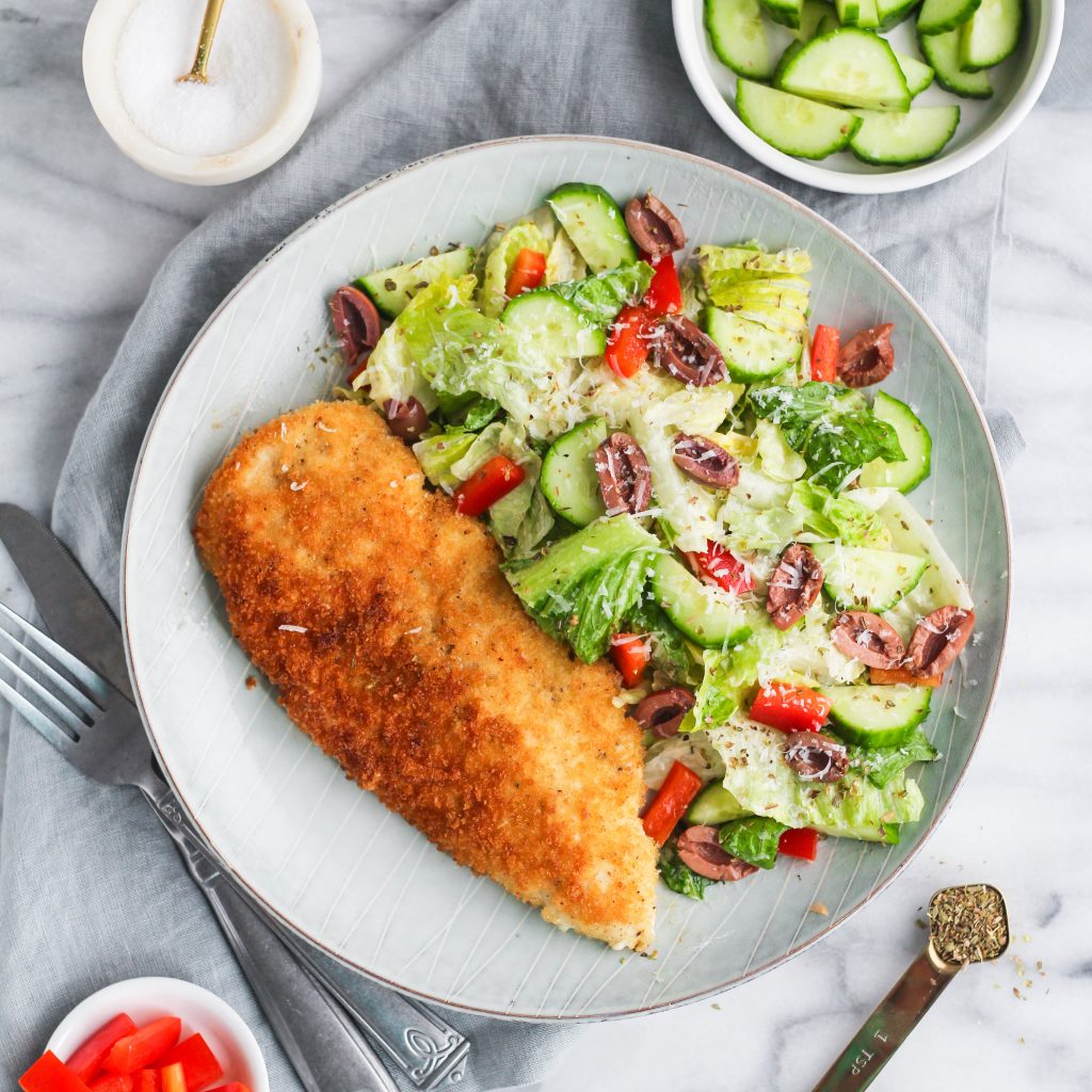 Chicken Milanese - a simple Panko breaded chicken breast, pan-fried in olive oil until golden brown. Served alongside a tangy creamy Italian style salad with crunchy peppers, cucumber, and olives. 