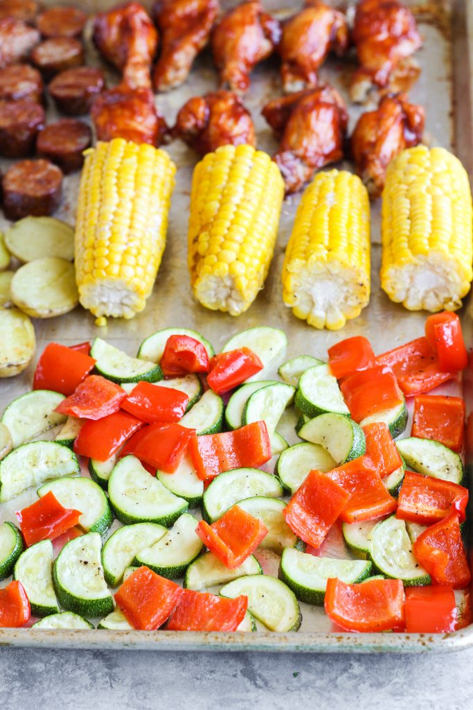 Create an entire barbecue dinner using just two baking sheet pans in under an hour! This recipe utilizes a stair-step method, meaning once the first item is in the oven (chicken), you’ll prep the second item and place in the oven (and so on). Fresh corn on the cob, tender buttery baby potatoes, roasted zucchini, and bell pepper pair deliciously with bourbon barbecue sauced wings and sausage.